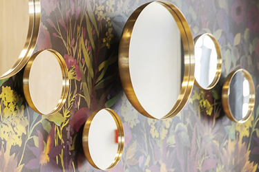 Wall with floral wallpaper and small round mirrors - Parking Andersen Hotel