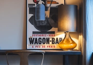 Desk with a picture frame and a tall table lamp – Hotel room at Maritime