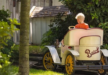 Barn kører i vintage Buick veteranbil på bane i grønne omgivelser i Tivoli