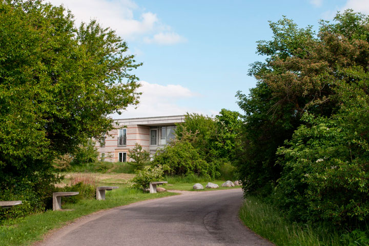 bygning i Ballerup med grønne træer og en gade som svejer