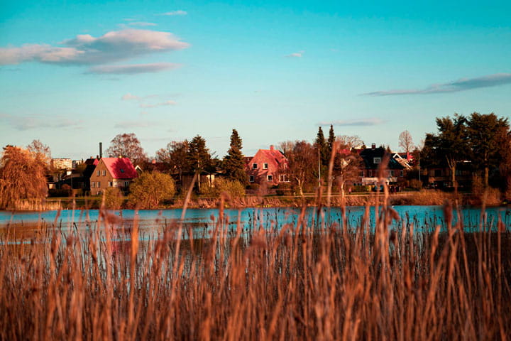 Brønshøj sø med bygninger på vandkanten og blå himmel