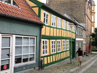 An old yellow house in Horsens. Person walks by
