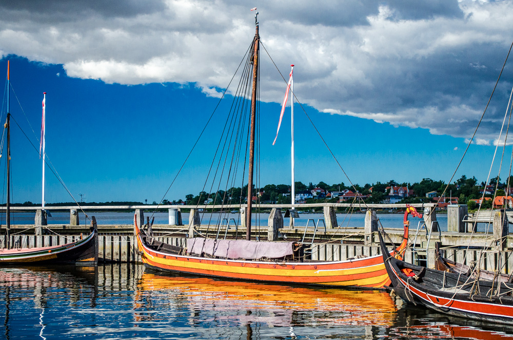 Roskilde havn med vikingeskibe ved dokken. Blå himmel og stille vand.