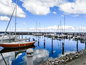 Rungsted småbådshavn med spejlblank vand og blå himmel.
