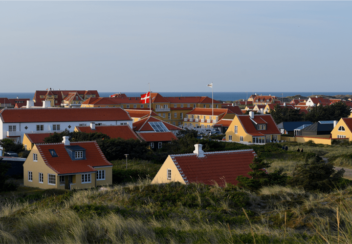 Skagens traditional yellow houses with red roofs in the sunset amongst the small beach hills.