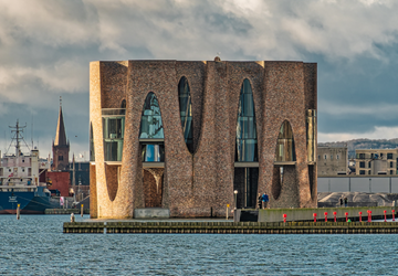 Fjordenhus house in Vejle. A building of cylinders in red brick and architectural glass panes.