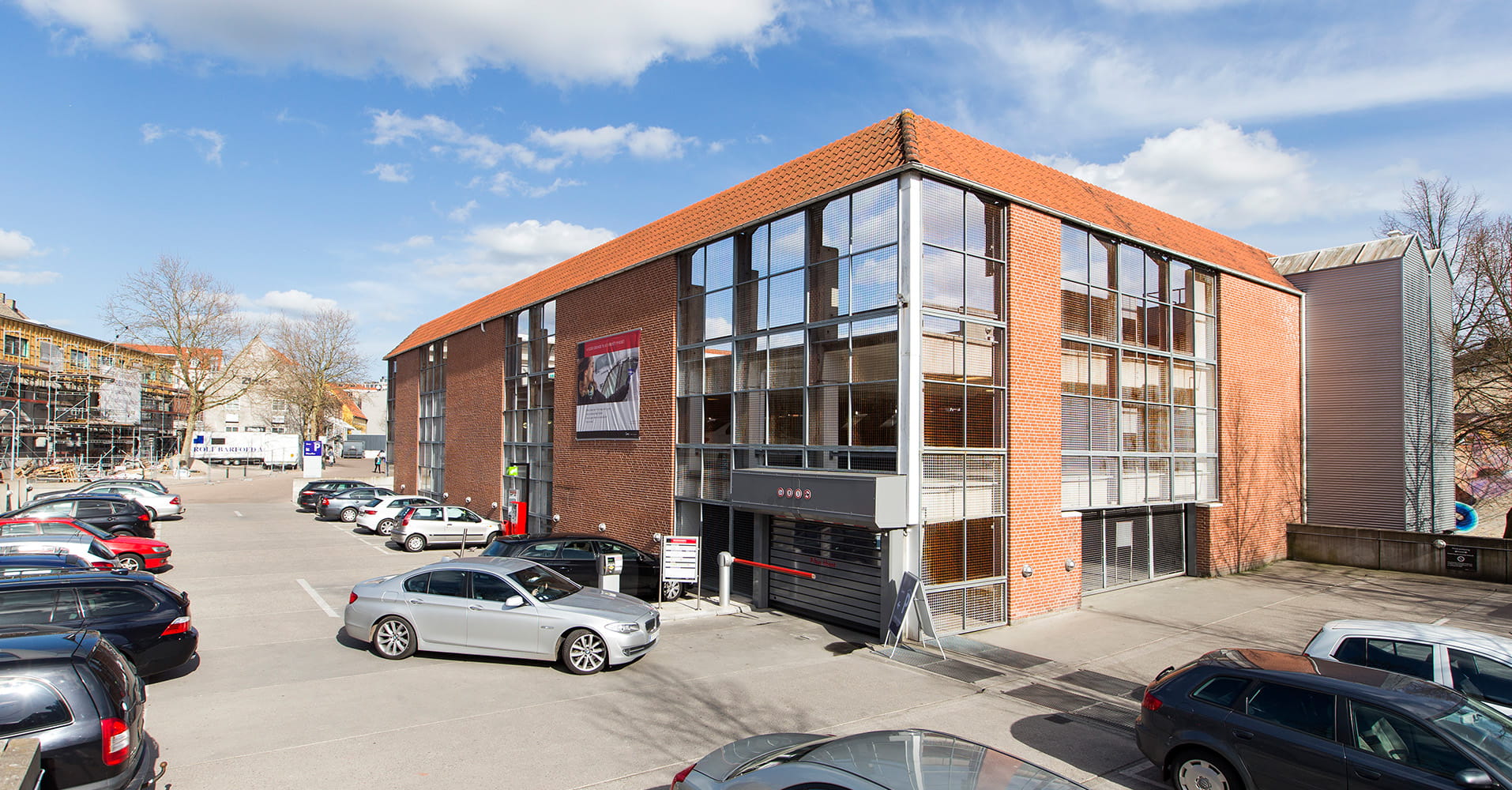 Q-Park Filosoffen bygning set udefra. Rød murstensbygning med biler parkeret omkring