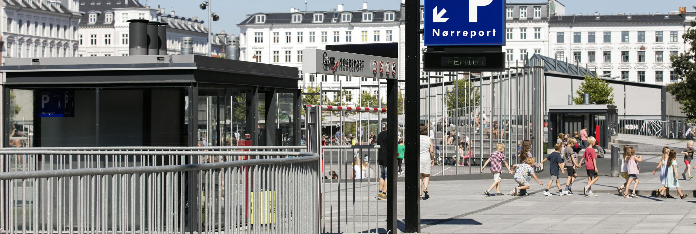 Q-Park nørreport above ground showing children playing and white buildings in the back